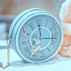 a small white pocket watch sitting on top of a table next to a teddy bear