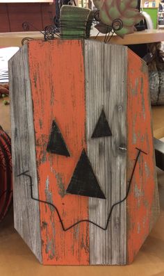 an orange and gray wooden block with two black triangles on it's face, sitting on a table