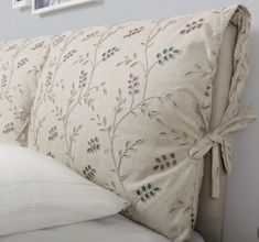 a close up of a pillow on a bed with pillows tied to the headboard