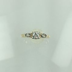 a diamond ring with three stones on the top and bottom, sitting on a white surface