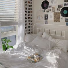 an unmade bed with white sheets and pictures on the wall above it in a bedroom