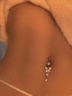 the back of a woman's stomach wearing a gold butterfly belly ring with diamonds on it