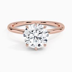 a rose gold engagement ring with a round brilliant cut diamond in the center, on a white background