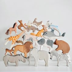 a group of wooden toy animals sitting on top of a white table next to each other