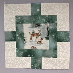 a quilted square with a dog and three dogs on it in the snow surrounded by trees