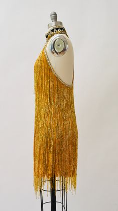 "80s Bob Mackie Super Chic Vintage Gold beaded and sequin dress features: * Silk chiffon body fully embellished with gold glass beads and stunning strands of beaded fringe * Beaded/sequined geometric pattern around neckline * Stunning t-strap back zip closure * Scalloped hemline * Fully lined with back zip closure * Great Vintage condition By Bob Mackie Boutique Size 6, fits like a small 100% silk Length from High point shoulder 33\" Bust 33\" Waist 30\" Hip 39\" All measurements are given in fu Flapper Style Sequin Dress For Summer Party, Summer Sequin Flapper Dress For Party, Summer Party Flapper Dress With Sequins, Summer Party Sequin Flapper Dress, Summer Embellished Flapper Dress For Costume Party, Summer Flapper Style Sequin Party Dress, Glamorous Gold Flapper Dress For Summer, Embellished Flapper Dress For Summer Costume Party, Summer Party Flapper Dress With Beaded Fringe