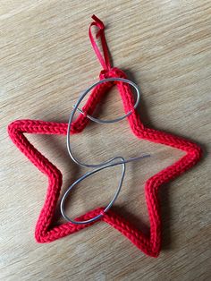 a crocheted star ornament hanging on a wooden table with metal hooks