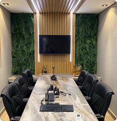 a long table with black chairs and a flat screen tv on the wall behind it