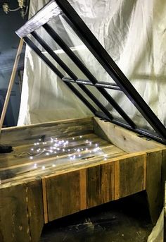 a wooden table with lights on it in front of a white sheet covered wall and ceiling