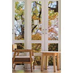 two chairs sitting next to each other on top of a hard wood floor in front of windows