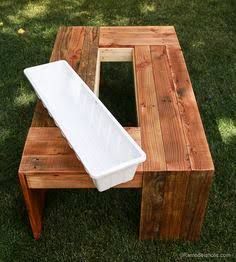 a table made out of pallet wood with a white container on top and some grass in the background