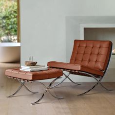 a modern chair and ottoman in front of a fireplace with a bowl on the table