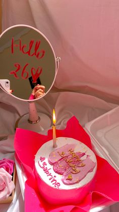 a birthday cake sitting on top of a pink napkin next to a mirror with writing on it