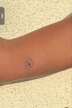 a person's arm with a small flower tattoo on the left side of their arm