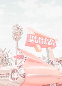 an old pink car is parked in front of a neon sign that says in - n - out burgerer