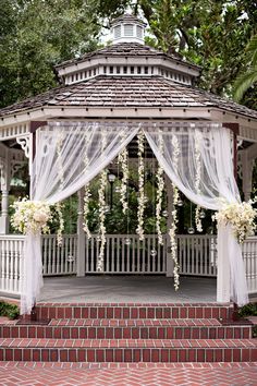 the wedding gazebo is decorated with white flowers