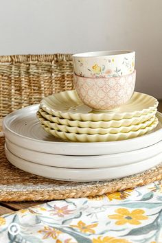 a stack of plates and cups sitting on top of each other in front of a wicker basket