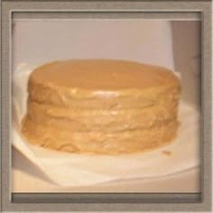 a cake with frosting sitting on top of a white table cloth covered in wax paper