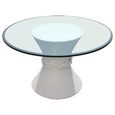 a glass table with a white base and round design on the top that is made out of ribbed material