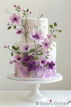 a three tiered cake with purple flowers on it