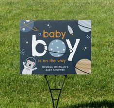 a baby boy is on the way sign in the grass with an astronaut themed background