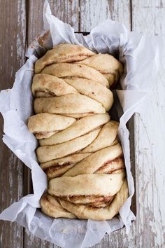 some bread is wrapped in wax paper on a wooden table