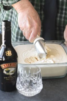 a man is mixing something in a bowl with a bottle next to it on the table