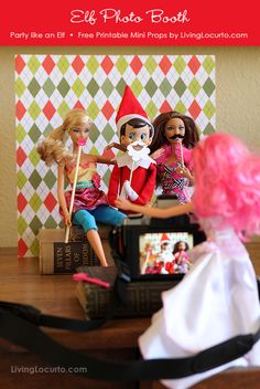 three dolls sitting on top of a wooden table next to a book and a camera