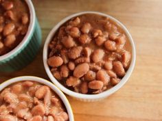 three bowls filled with beans sitting on top of a wooden table