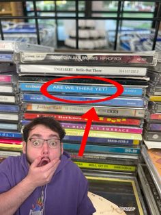 a man with his mouth open in front of a stack of cds and records on display