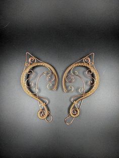 Just the right touch to spice up your fantasy costume. Add these beautiful ear cuffs to your elf costume for your next Ren Faire or use them as a fun bit of jewelry at your next D&D event. Golden Brass and Copper curls with intricate woven wire with a clear finish make these lovely ear cuffs a must have for your next fantasy event.  These ear cuffs have been polished to a bright shine and sealed with a clear coat. No piercings are necessary for these elf ears to stay in place, the back wire rides behind the ear similar to a pair of glasses and the front decorations provide gentle pressure to keep the cuffs in place. Each cuff is approximately 4 inches in height and 2 inches in width. Fantasy Festival Earrings, Handmade Bohemian Costume Jewelry, Handmade Fantasy Earrings For Festivals, Adjustable Fantasy Wrap Earrings As Gift, Adjustable Fantasy Wrap Earrings For Gift, Handmade Fantasy Wrap Earrings As A Gift, Adjustable Handmade Cartilage Earrings For Festivals, Handmade Adjustable Cartilage Earrings For Party, Fantasy Style Party Earrings