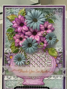 a card with purple flowers in a vase