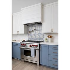 a stove top oven sitting inside of a kitchen next to white cupboards and drawers