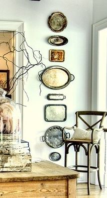 a living room filled with furniture and plates hanging on the wall behind a glass dome