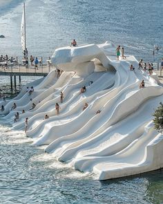 many people are swimming in the water near an artificial wave pool that is designed to look like a boat