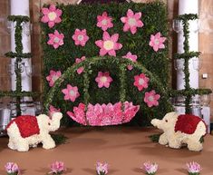 some pink and white flowers are in front of a fake flower display with two elephants