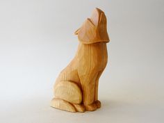 a wooden dog statue sitting on top of a white surface