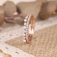 a close up of a ring with pearls and diamonds on it's side, sitting on a piece of lace