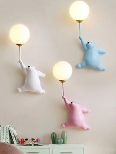 three little bears are hanging on the wall and one is holding a light up to it's head