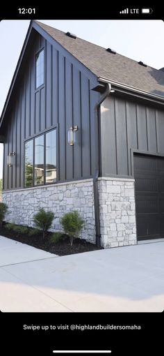 a house that is made out of wood and has stone on the front, along with two garage doors