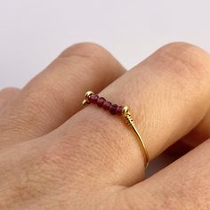 This beautifully simple ring is lovingly handmade with 5 tiny Garnet gemstones and a choice of 14k Gold Filled, 14k Rose Gold Filled or Sterling Silver band. M A T E R I A L S: * Garnet * 14k Gold Filled, 14k Rose Gold Filled or Sterling Silver S I Z E: *  Gemstone - Approximately 2mm each *  Band Thickness - Approximately 0.8-1mm  All of our jewellery is carefully handmade using good quality materials and handpicked gemstones, with the aim to produce quality pieces that you can love & wear for Adjustable 14k Gold Ruby Promise Ring, Adjustable 14k Gold Ruby Ring For Anniversary, Handmade Minimalist Adjustable Birthstone Ring, Handmade Adjustable Minimalist Birthstone Ring, Handmade Adjustable Yellow Gold Birthstone Ring, Adjustable 14k Gold Midi Rings With Birthstone, Minimalist Stackable Adjustable Ruby Ring, Handmade Dainty 14k Gold Birthstone Ring, Dainty Stackable 14k Gold Ruby Ring