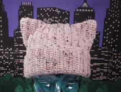 a knitted hat on top of a mannequin's head in front of a cityscape