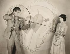 an old black and white photo of two people in front of a heart with arrows