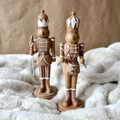 two wooden nutcrackers sitting on top of a white blanket