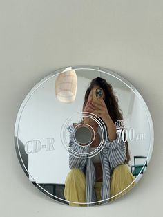 a woman taking a selfie with her cell phone in front of a circular mirror