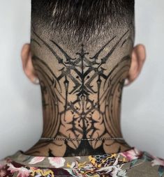 the back of a man's head with tattoos on his face and neck area