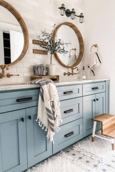 a bathroom with blue cabinets and two round mirrors