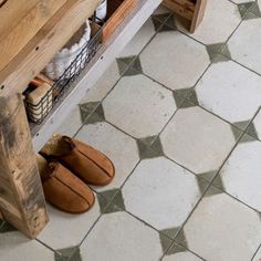 a pair of brown slippers sitting on top of a wooden bench next to a tiled floor