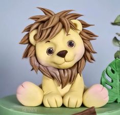 a lion figurine sitting on top of a green table next to a plant