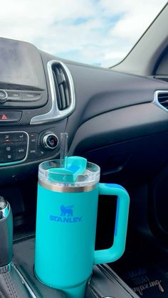 a car dashboard with a cup, phone and other items on the dash board in front of it